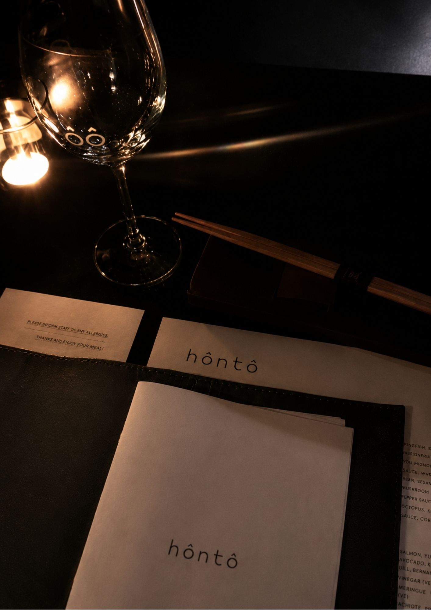 The honto menu on a dark table with a wine glass, at the hidden Japanese restaurant in Fortitude Valley, Brisbane