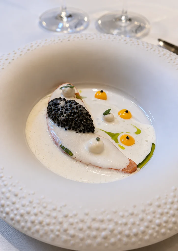 Fine-dining dish topped with caviar in a textured white bowl