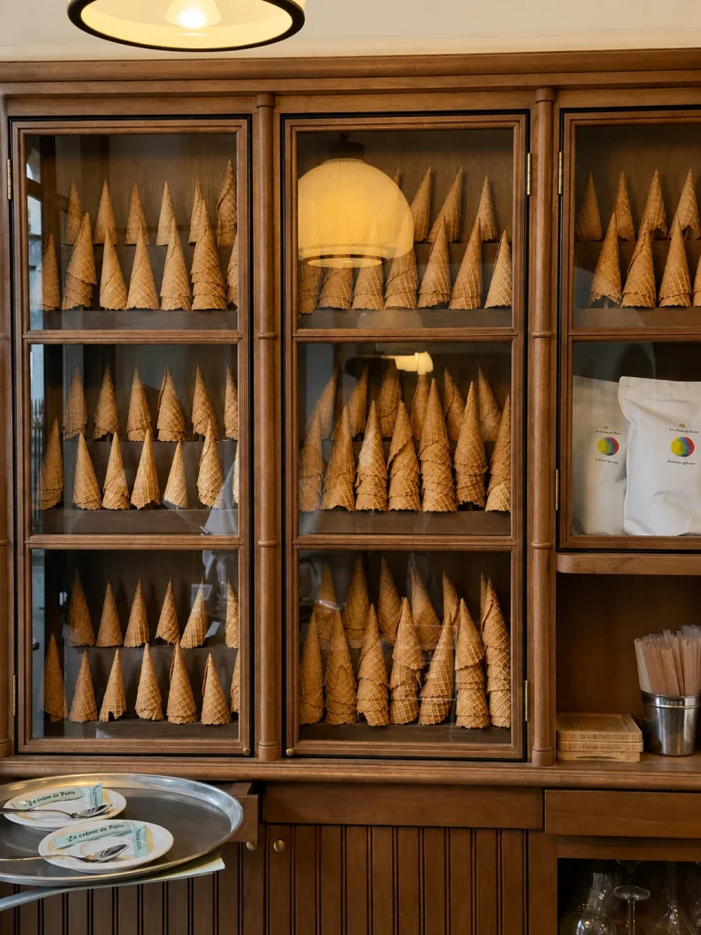 Wooden shelves holding rows of waffle cones in an ice cream shop
