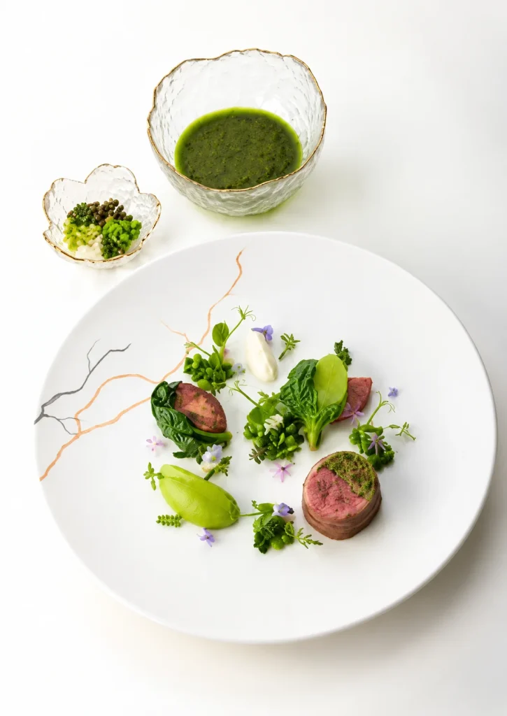 Plated meat dish with green herb sauce and vegetables on a white plate