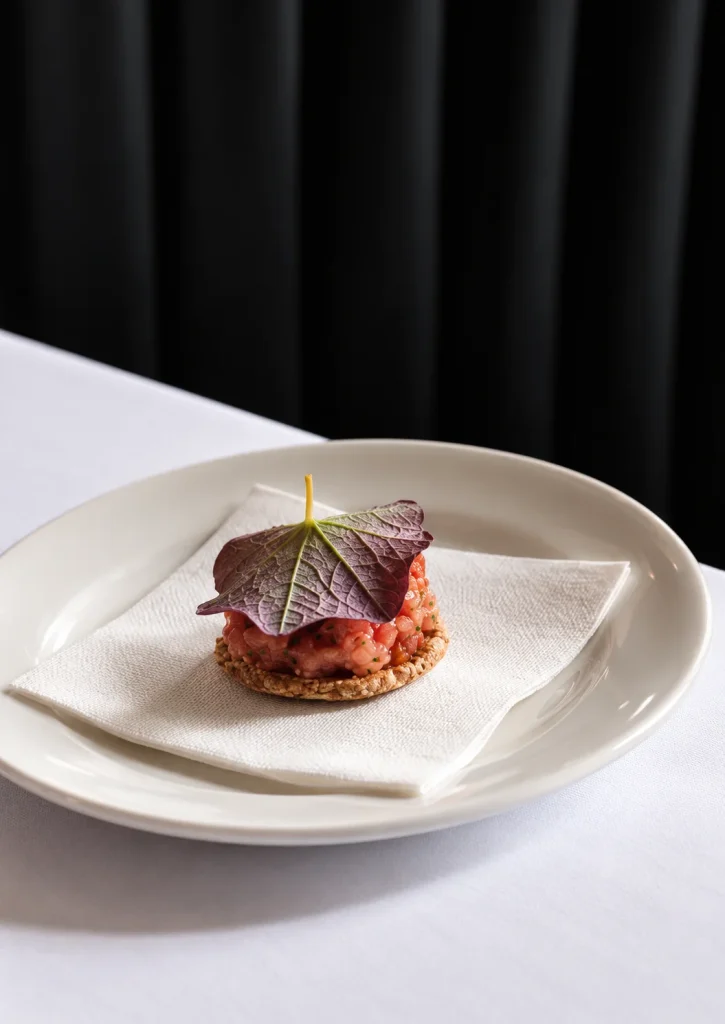 Small plated tart with a purple leaf garnish on a white napkin