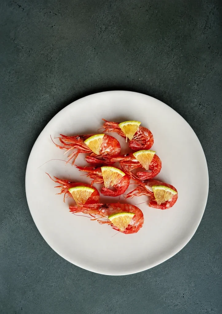 Plate of red prawns with lemon wedges on a dark green surface