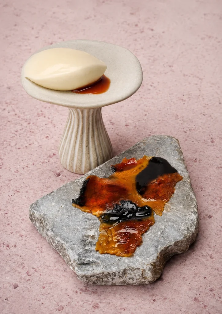 A sculptural dessert served on a stone slab against a pink wall in Bali