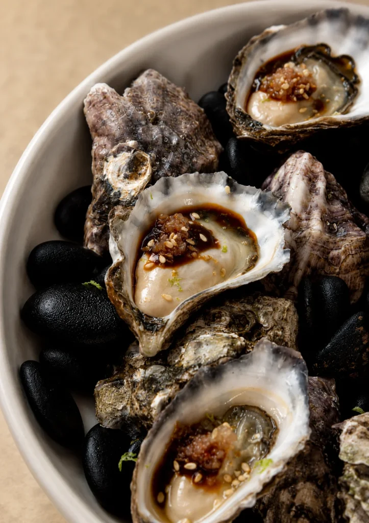 Grilled oysters served on black stones at a Byron Bay restaurant