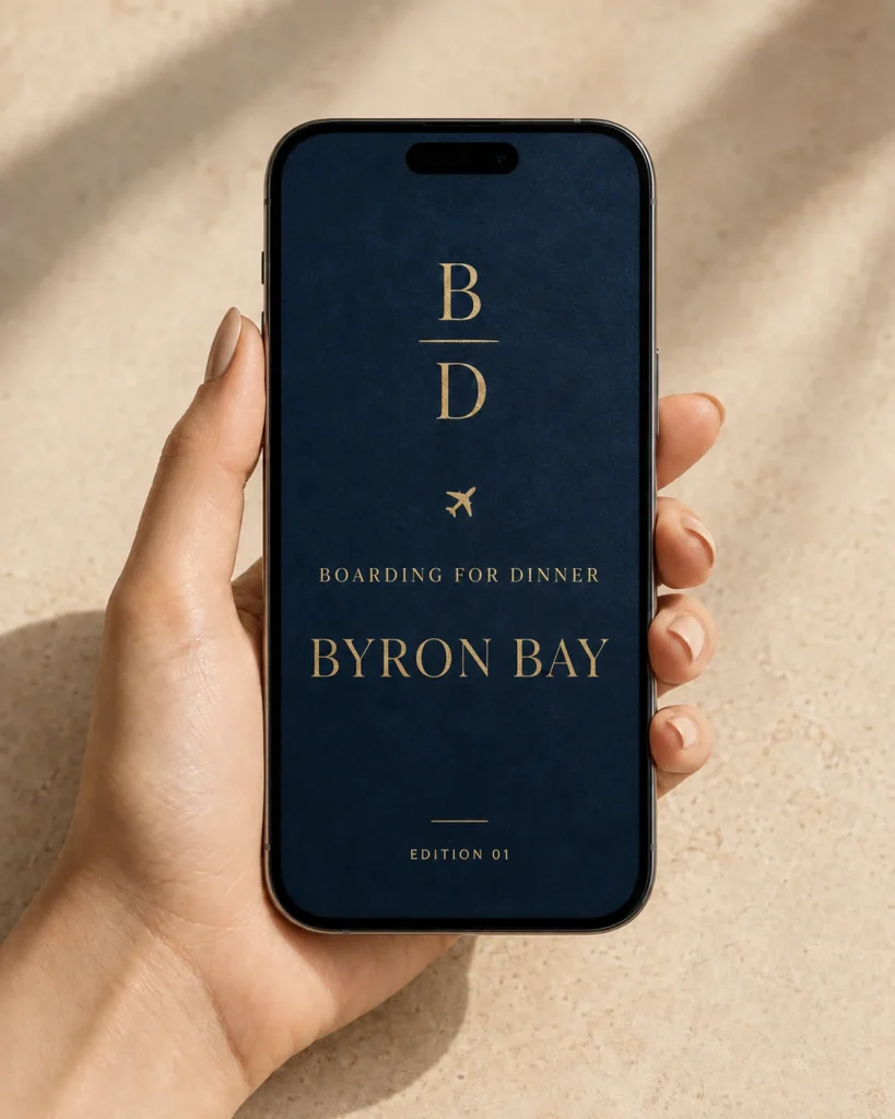 A hand holding a phone showing the Byron Bay Food Guide cover