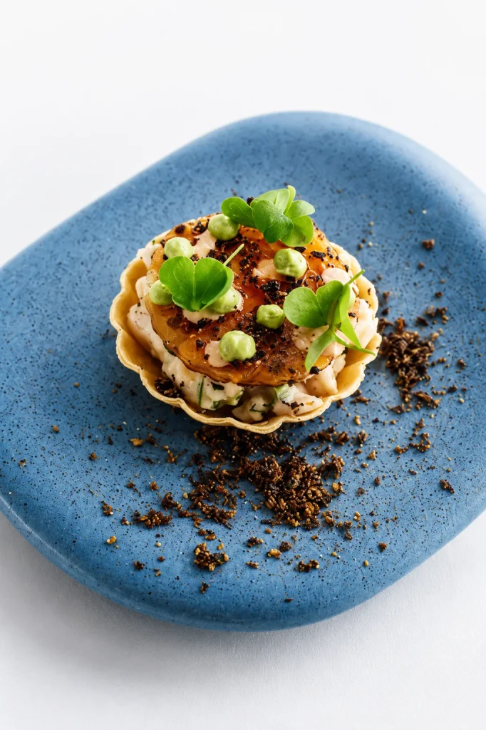 Tartlet with crab and fresh herbs on a blue ceramic plate