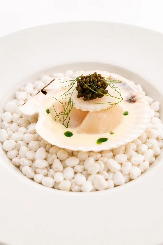 Scallop served in the shell on a bed of pearls