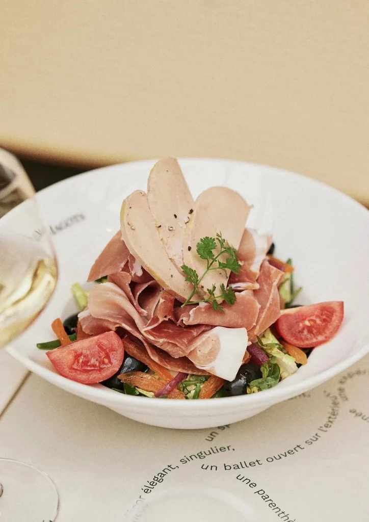 Salad bowl with cured ham, figs and greens on a café table