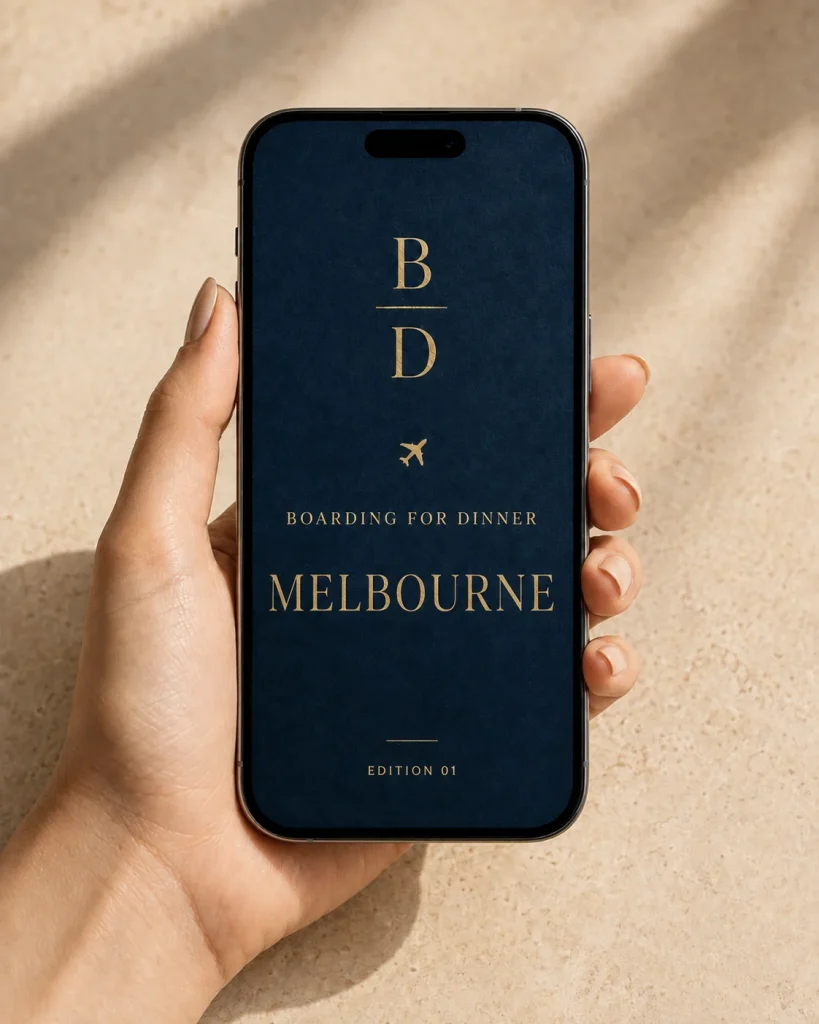 A hand holding a phone showing the Melbourne Food Guide cover