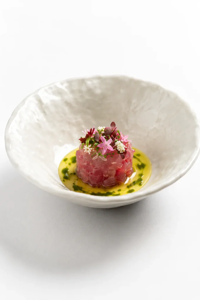 Tuna tartare with herb puree served in a white bowl